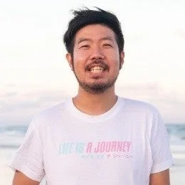 白いTシャツを着て笑顔で写るアジア人男性のポートレート