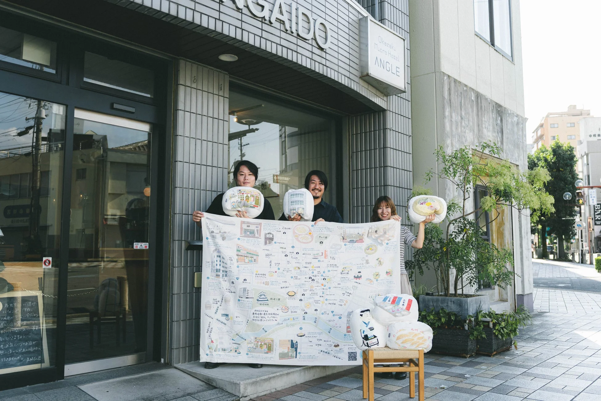 企画関係者がクッションとマップを持つ様子