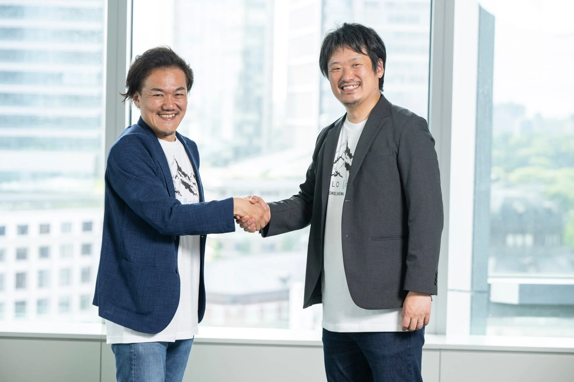 明るいオフィスで二人の男性が笑顔で握手を交わしている