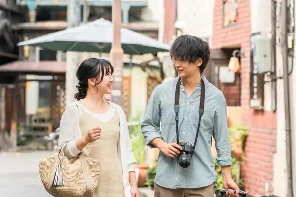 若いカップルが笑顔で街並みを歩いています