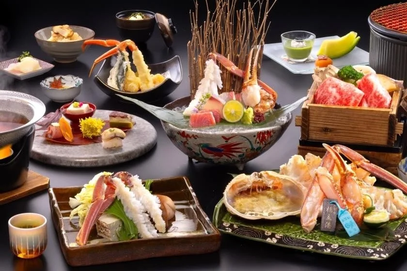豪華な日本料理のフルコースが並べられた写真。松葉ガニ、刺身、天ぷら、和牛など、贅沢な食材が美しく盛り付けられている。