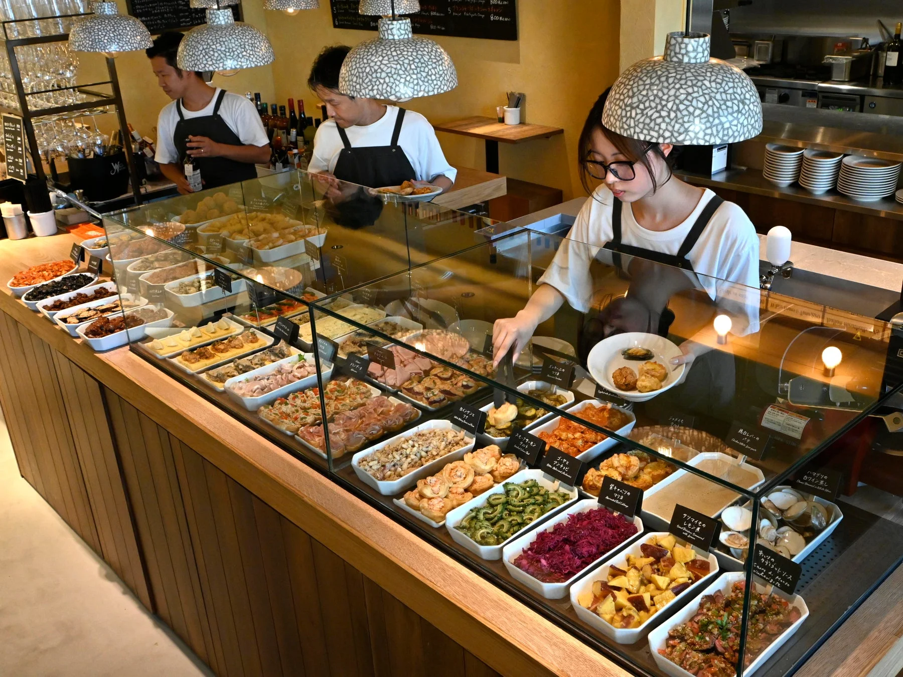 デリ、ビュッフェ、惣菜、イタリアン、レストラン、食事、料理、ショーケース、サラダ、パスタ、肉料理、チーズ、食材、ワイン、接客、人々、活気、グルメ、カフェ