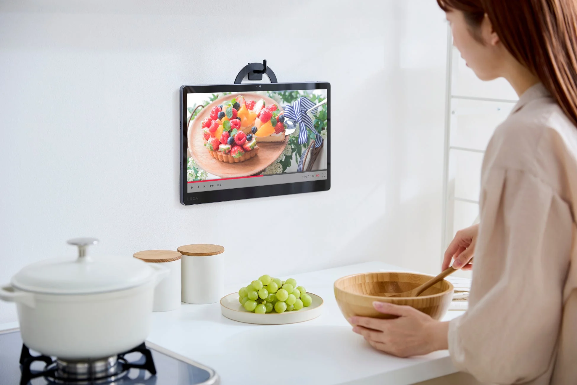 キッチンで壁掛けタブレットを見る女性