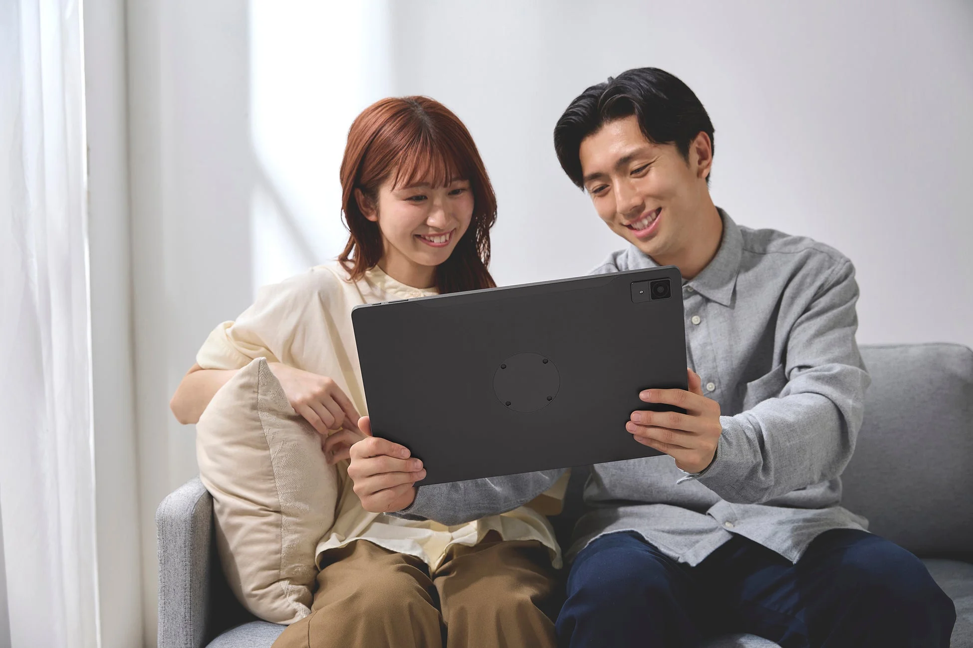 ソファでタブレットを見るカップル