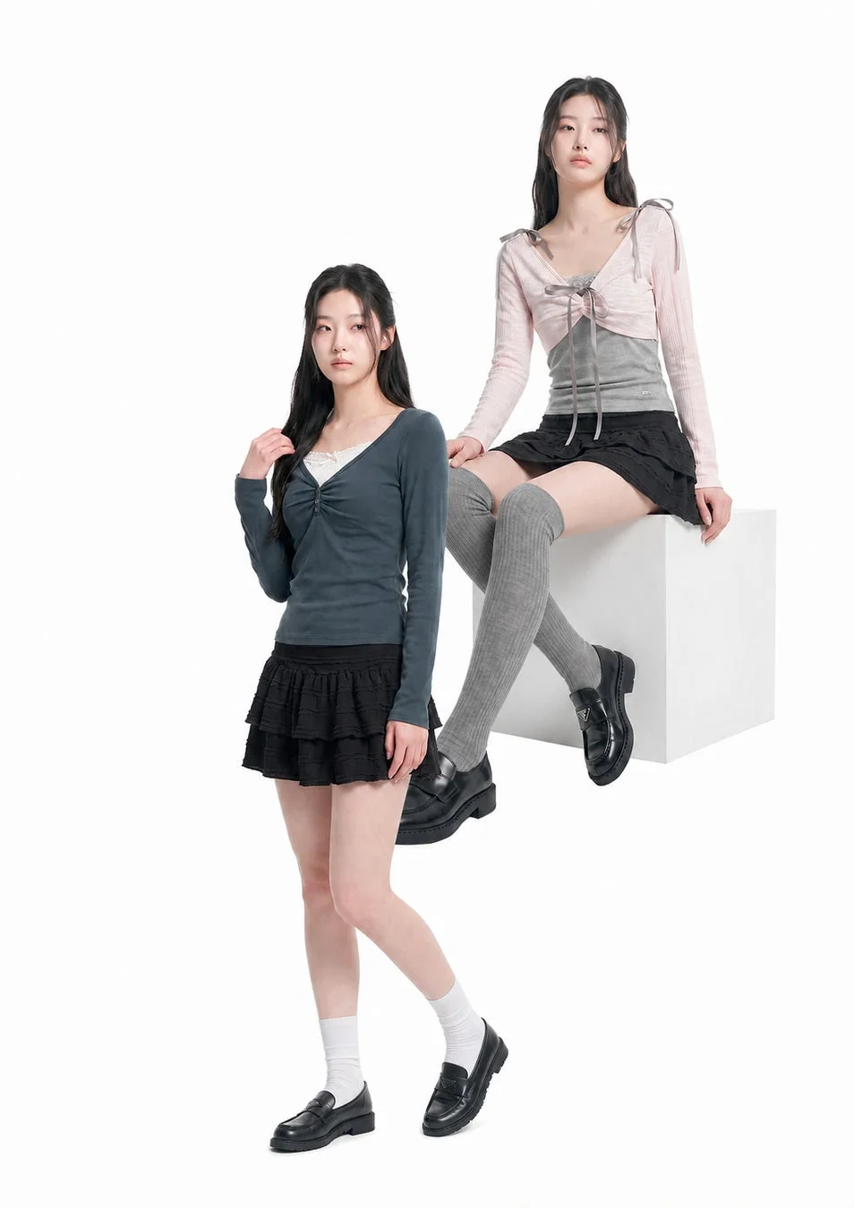 長袖トップス、黒のミニスカート、ローファーを着用した2人の若い女性