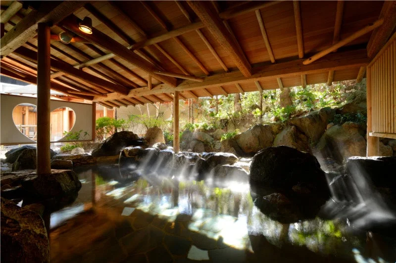 木造の屋根と岩に囲まれた開放的な露天風呂の風景