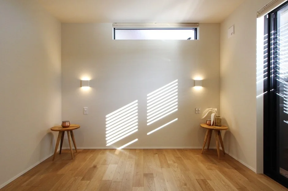 白い壁と明るい木製フローリングのミニマルな部屋