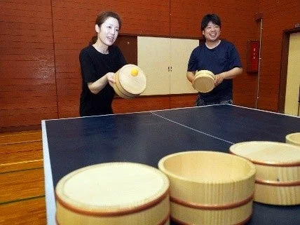 木桶をラケット代わりに卓球を楽しむ人々