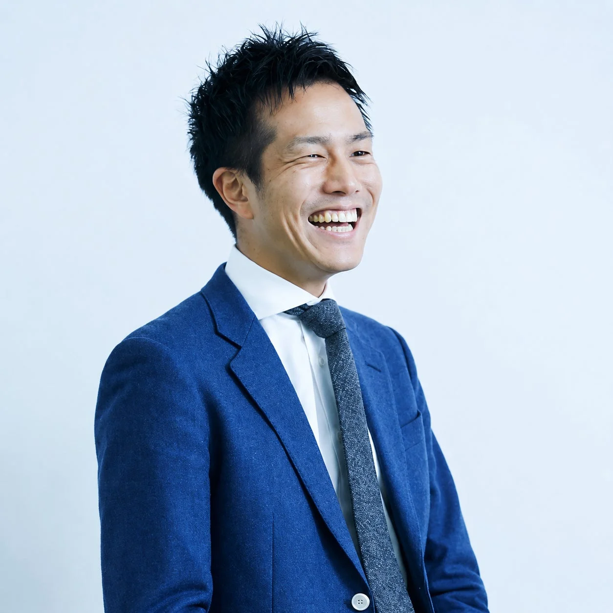青いスーツを着て笑顔の男性